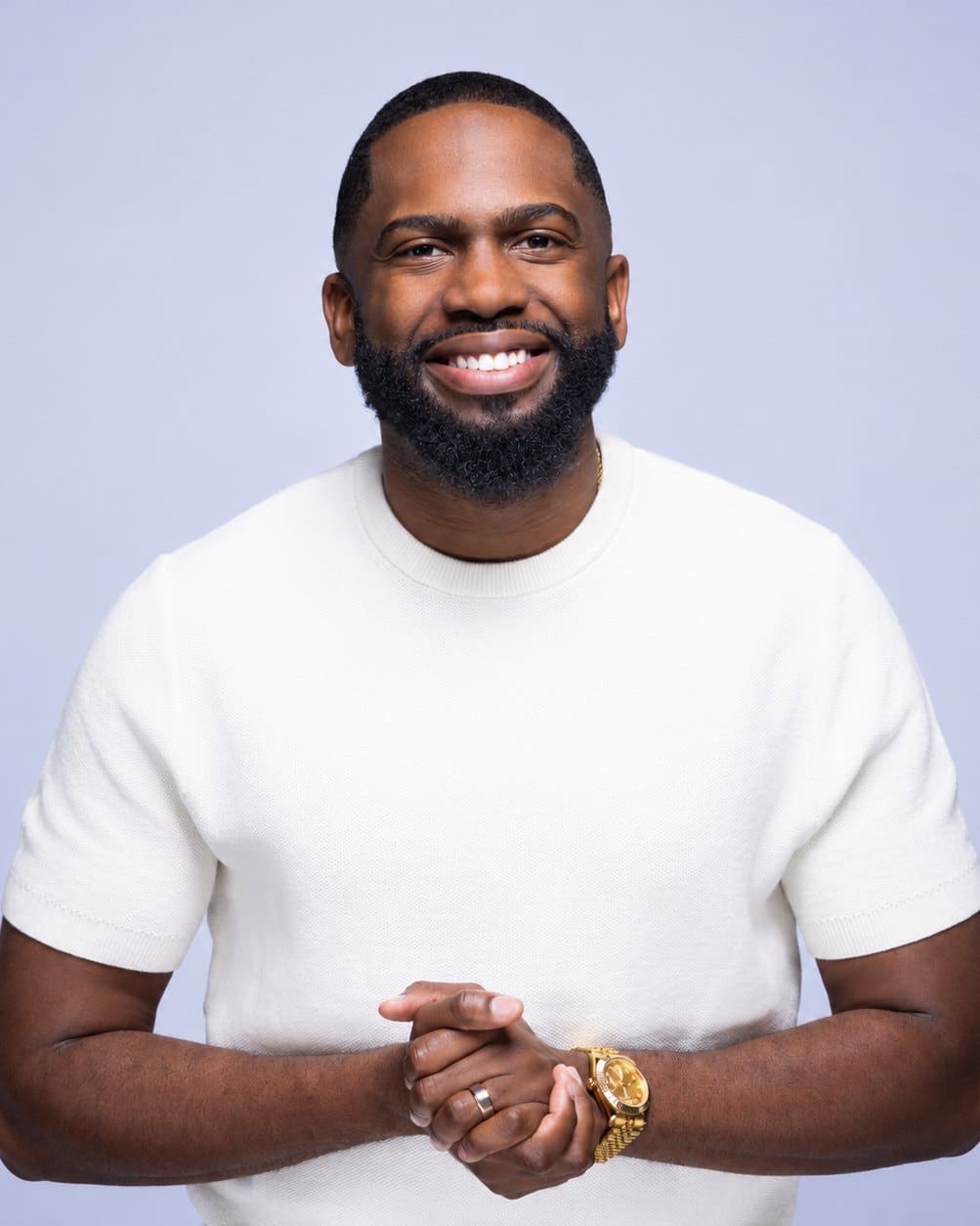 Ronald Richardson smiling in a white knit shirt, hands clasped