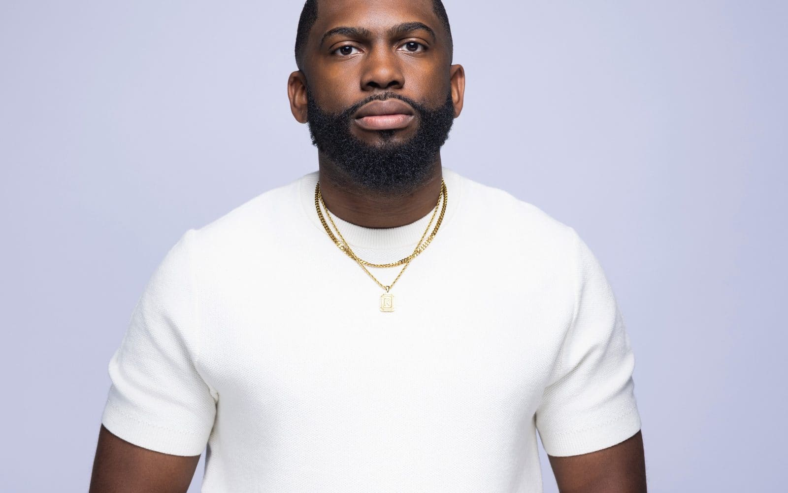 Ronald Richardson in a white knit shirt, hands steepled